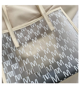 Macro detail of clear tote bag featuring monogram M print and beige leather handles