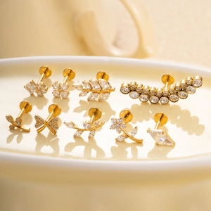 Golden titanium flower stud earrings with zirconia crystals on white tray