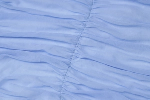 Detailed macro view of the blue pleated fabric texture and stitching for a backless dress