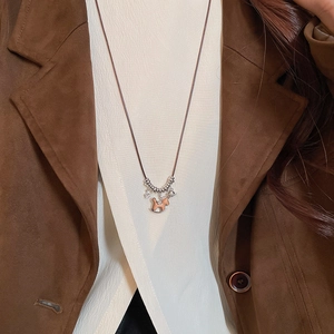 Detailed view of brown wooden rocking horse pendant on long retro sweater necklace