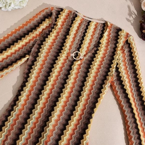 Detail of chevron knit dress featuring V-neckline with a decorative metal ring element