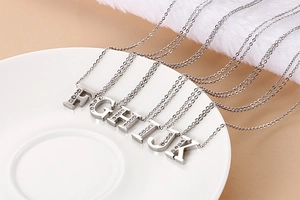 Close-up of silver stainless steel necklaces with sparkling crystal alphabet pendants F-K
