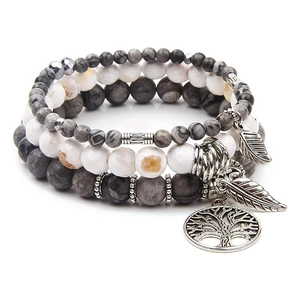 Detail of tree of life charm and feather pendants on marble beaded bracelets set
