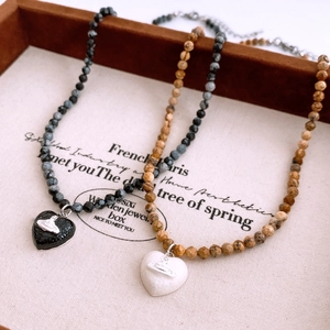 Detail of vintage heart pendants with Saturn ring logo on natural stone bead necklaces
