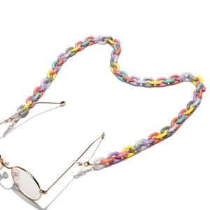 Macro shot of colorful acrylic chain links attached to gold glasses on white background