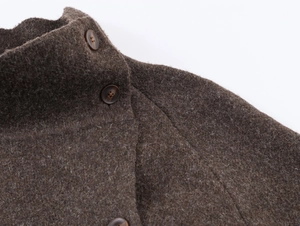 Détail de la texture du manteau en laine marron et de la fermeture à bouton de qualité