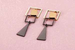 Detail of geometric gold and black mismatched square and triangle long drop earrings