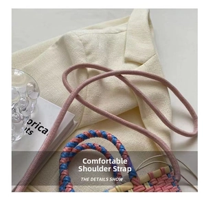 Close-up of colorful woven bucket bag featuring pink shoulder strap and detailed texture
