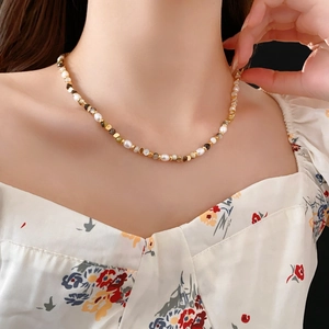 Close-up of elegant freshwater pearl necklace with gold beads on floral background