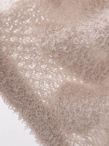 Nahaufnahme von weichem cremeweißem Strickstoff mit flauschiger Textur und Muster