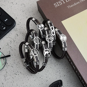 Braided leather bracelets for men with silver stainless steel charms on a grey surface