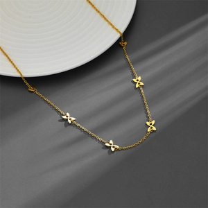 Collier ras du cou élégant en acier doré avec petits pendentifs papillons sur fond gris