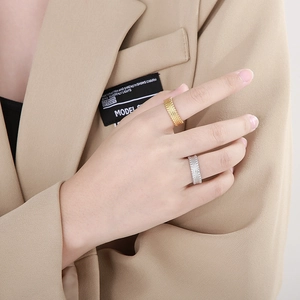 Detail of layered wavy texture on gold and silver titanium steel rings worn on hand