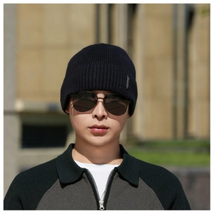 Detail of navy knit beanie featuring ribbed texture and small silver metal tag accent