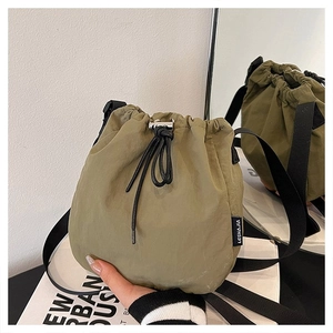Detail of army green drawstring bucket bag with black strap and metallic hardware