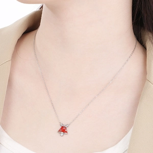 Detail showing a silver chain necklace with a red Christmas bell pendant and snowflake