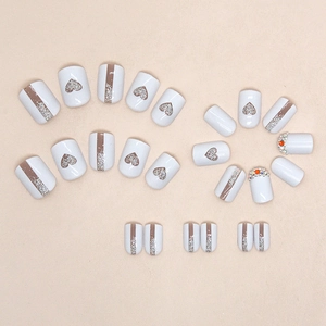 Faux ongles avec cœurs évidés, paillettes argentées et strass en blanc et marron
