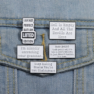 Set of 5 black and white enamel pins with humorous quotes pinned on a denim jacket