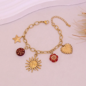 Close-up of golden charm bracelet with sun, star and red floral enamel pendants