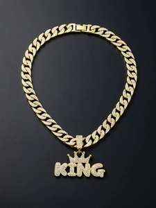 Macro shot of gold Cuban chain necklace with iced-out KING pendant and crown