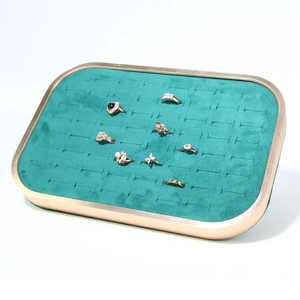 Detail view of green velvet jewelry tray with gold metal frame and ring slots