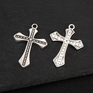 Vintage silver zinc alloy cross pendants with dotted texture on a dark slate background