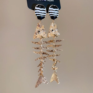 Detailed close-up of fishbone drop earrings with gold hammer texture and enamel details