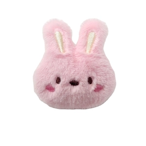 Cute pink plush rabbit brooch with embroidered expression on a white background