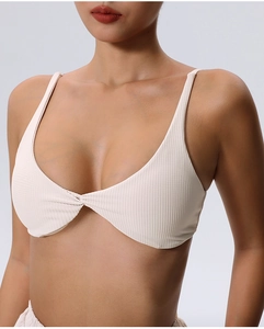 Detail shot of off-white ribbed sports bra featuring a twisted knot and thin straps
