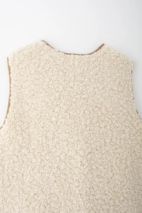 Vue détaillée de la texture polaire crème avec bordure marron sur le haut du gilet