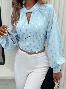 Detail of V-neckline and gold polka dot pattern on blue long sleeve blouse top