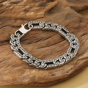 Detailed view of vintage silver NK chain bracelet with engraved patterns on wood