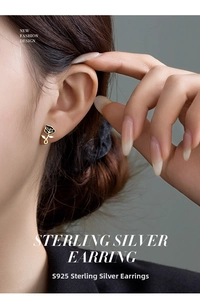 Detail of S925 silver vintage black rose earrings with gold edges on model ear