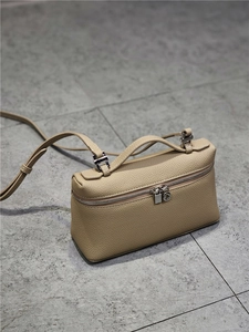 Detail of beige lychee leather bag with silver zipper, top handle and slim strap
