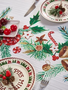 Detalle de mantel navideño con campanas tejidas, bastones de caramelo y ramas de pino