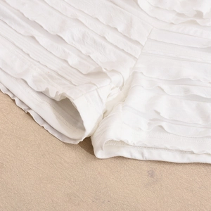 Détail de plis multicouches et coutures fines sur le haut court blanc dos nu