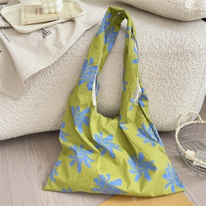 Detail of avocado green canvas tote with blue floral print on a cozy sofa