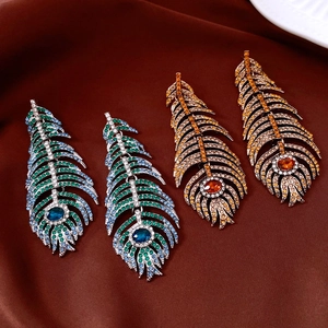 Macro detail of vintage crystal feather earrings with teardrop center stones in two colors