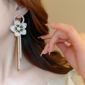 Détail de la boucle d'oreille fleur en résille avec perles et pompons de cristal