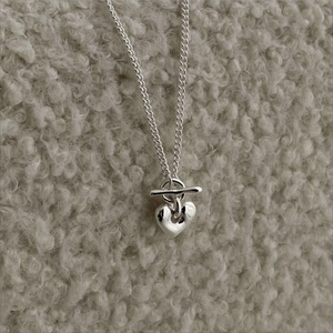 Detail of silver heart pendant necklace with T-bar toggle clasp on a textured surface