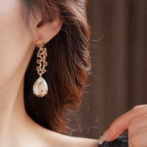 Close-up of elegant gold drop earrings with champagne teardrop crystals on a model