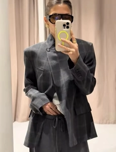 Détail d'un blazer à carreaux gris foncé avec une fermeture à bouton croisé asymétrique