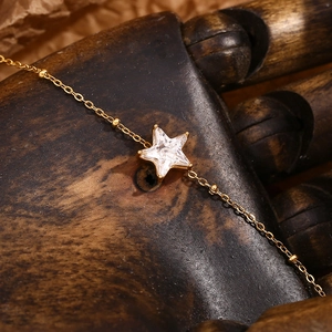 Macro shot of 18K gold plated star bracelet with inlaid crystals on a wooden hand