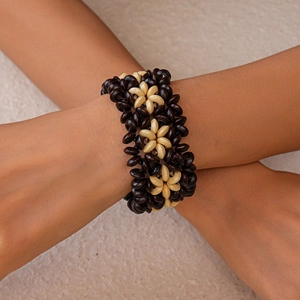 Détail d'un bracelet bohème en perles de bois avec motifs floraux crème et marron foncé