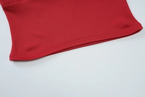 Vue détaillée de la couture et de la texture du tissu sur l'ourlet d'un top rouge