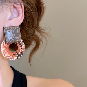 Close-up of vintage drop earrings with wooden square stud and orange bamboo pattern pendant