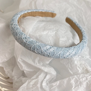Close-up of light blue lace headband with hollow floral pattern and soft suede lining