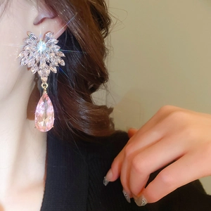Détail macro de boucles d'oreilles avec cristal rose en goutte et motif floral en zircon