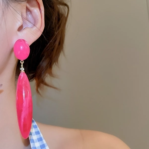 Detail of hot pink resin drop earrings with marble texture on a female model