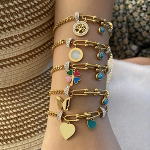 Gros plan de bracelets en acier doré avec breloques cœur et papillon sur un mannequin